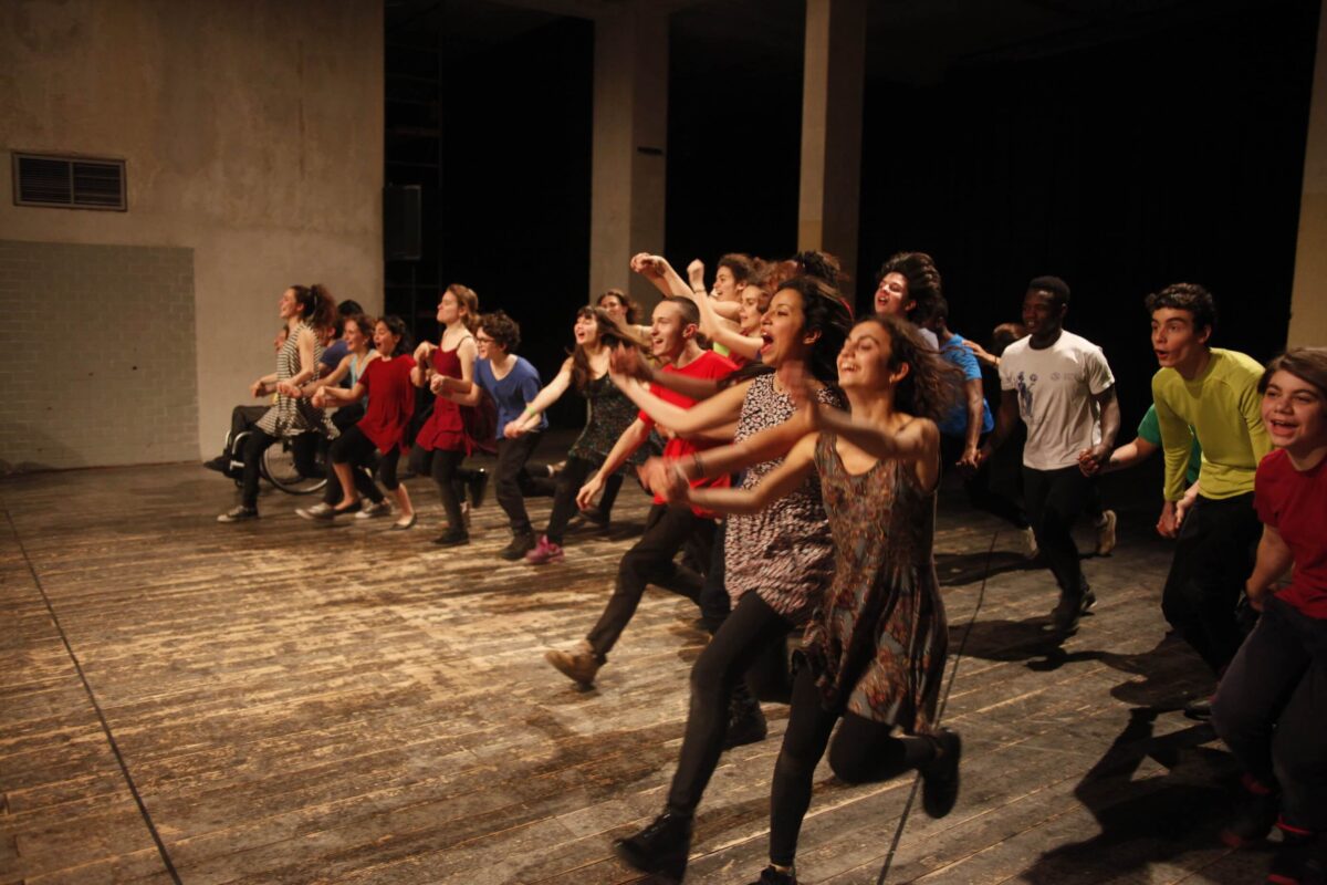 Azione collettiva di ragazze e ragazzi in corsa sul palco durante il progetto non-scuola al TeatroLaCucina