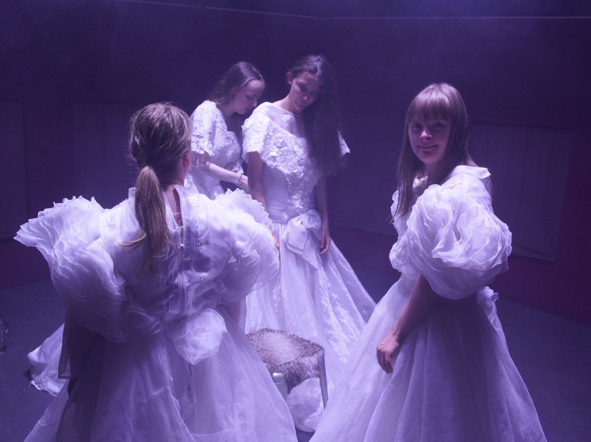 Ragazze in abiti bianchi, eleganti e fiabeschi che si aiutano nel vestirsi prima di entrare in scena per lo spettacolo Un peep show per Cenerentola