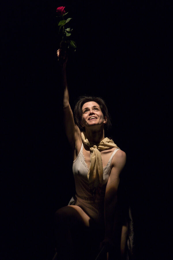 Una donna guarda fissa di fronte a sé, col braccio destro alzato, riprendendo la gestualità e i movimenti dell'eroina del quadro la libertà che guida il popolo di delacroix