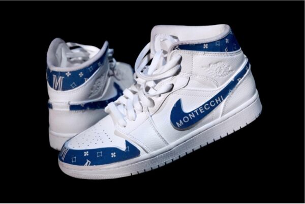 Su fondo nero, un paio di scarpe da basket bianca modello Nike, con i profili blu e la scritta Montecchi
