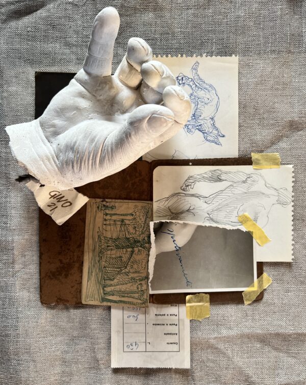 Un calco in gesso di una mano sta appoggiato su una composizione di fotografie e bozze di disegni, tutti in una tonalità tra il sabbia, beige, su un tavolo che sembra di marmo