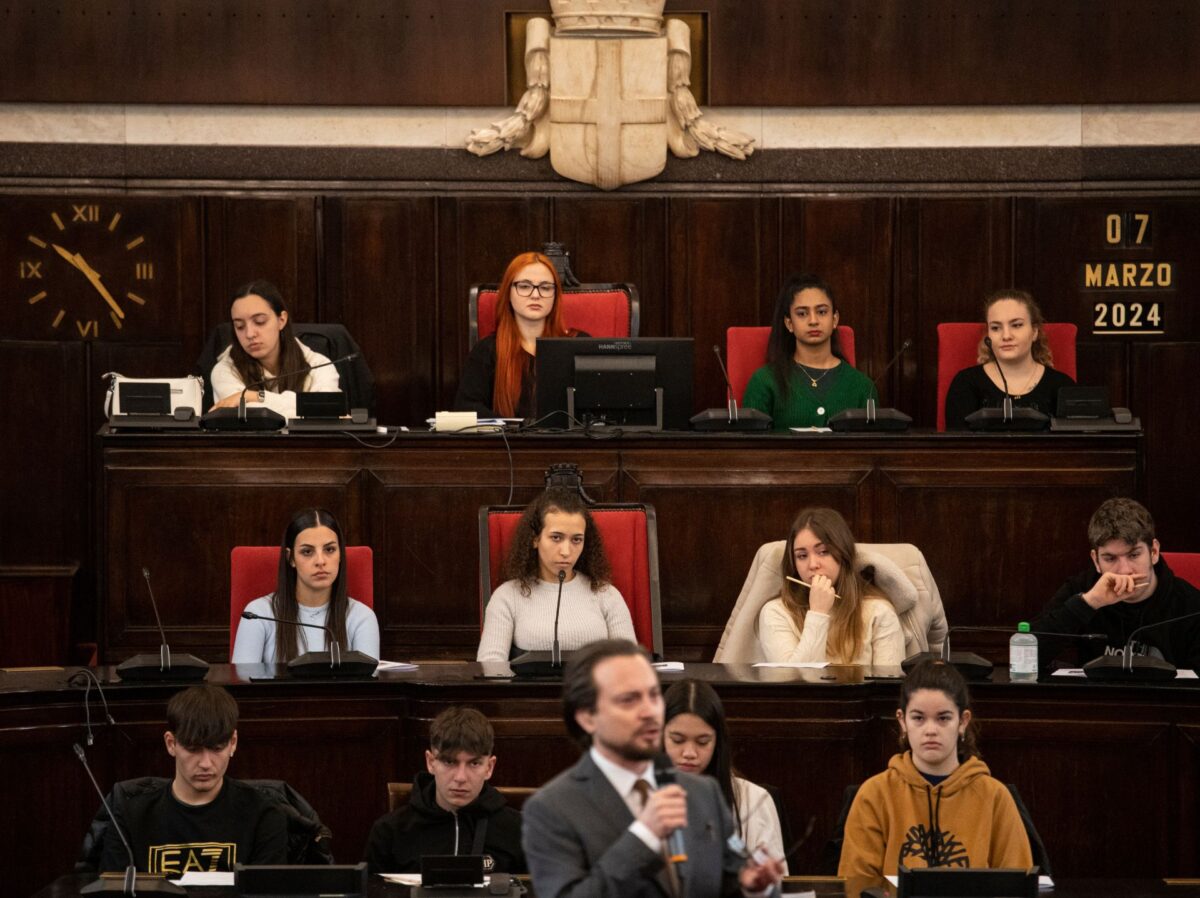 In primo piano l'attore che interpreta primo levi, dietro sugli scranni dell'aula del consiglio comunale studenti e studentesse di quinta superiore