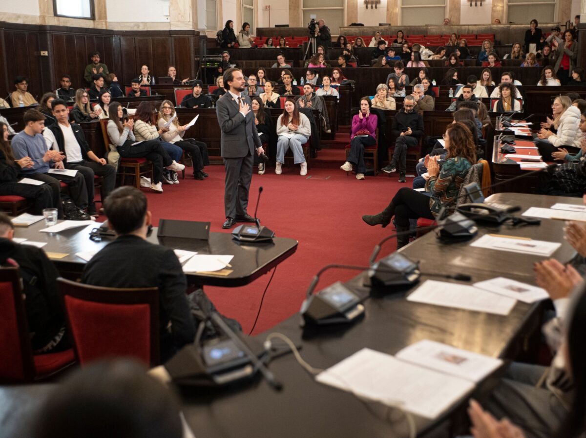 L'attore che interpreta Primo Levi sta al centro della scena nell'aula consiliare di palazzo marino, seduti sugli scranni dei consiglieri studentesse e studenti di quinta superiore