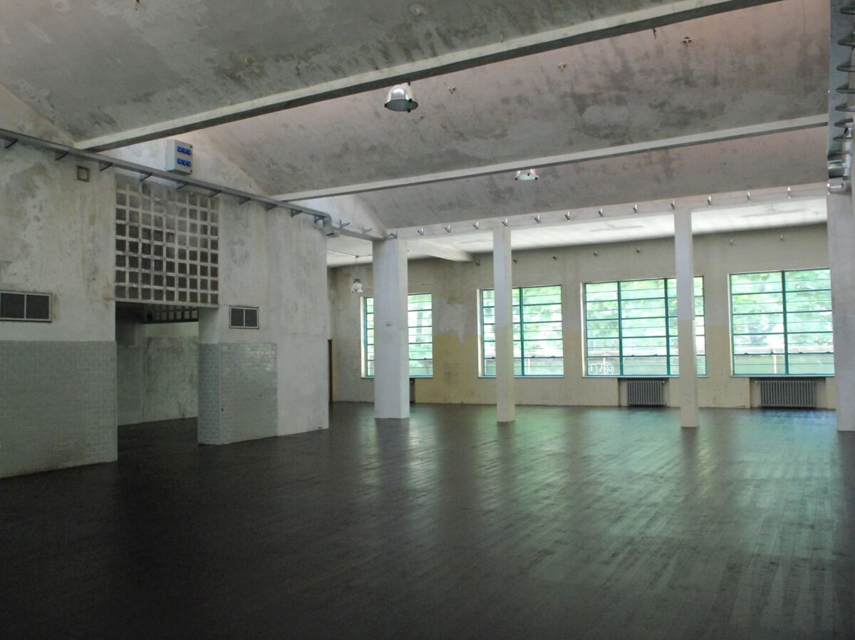 Sala e palcoscenico del teatrolacucina, ex mensa dell'ospedale psichiatrico paolo pini, con architettura industriale e ampie finestre sul fondo